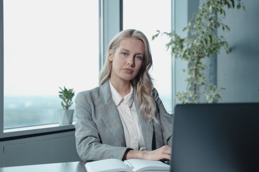 pexels-photo-5717550-5717550 Professional businesswoman at a desk in a bright office with a laptop and notebook.